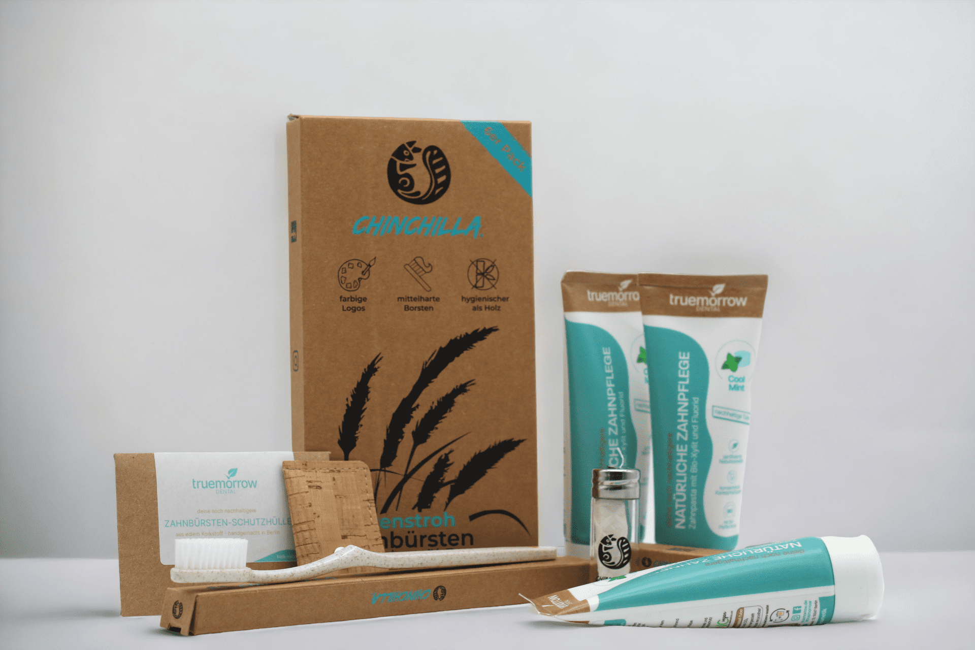Nachhaltige Zahnbürste, Zahnpasta, Zahnseide und eine Schutzhülle vor weißem Hintergrund